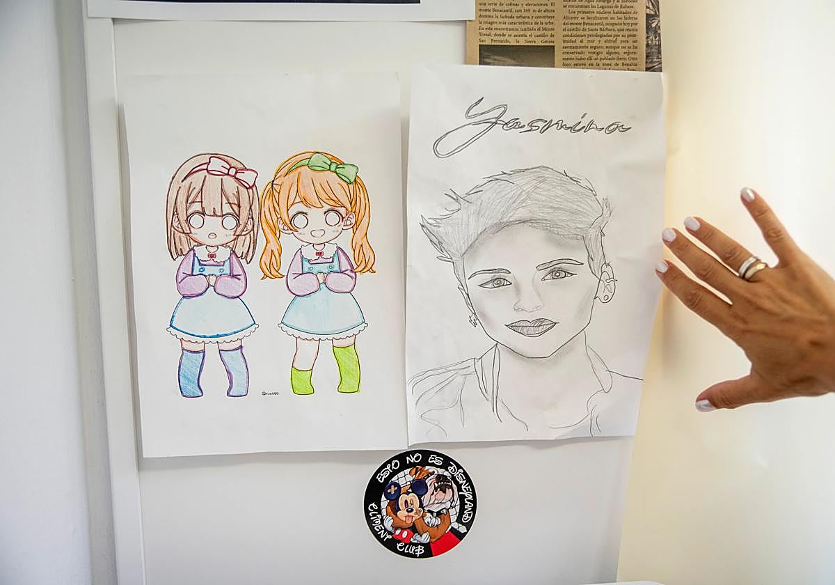 Yasmina muestra un retrato hecho por 'sus niños' del centro de menores y un dibujo. Debajo, una pegatina: 'Esto no es Disneyland'.