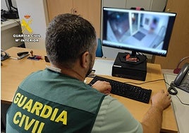 Un investigador de la Guadia Civil observa a la sospechosa sacando dinero de las cámaras del cajero automático.