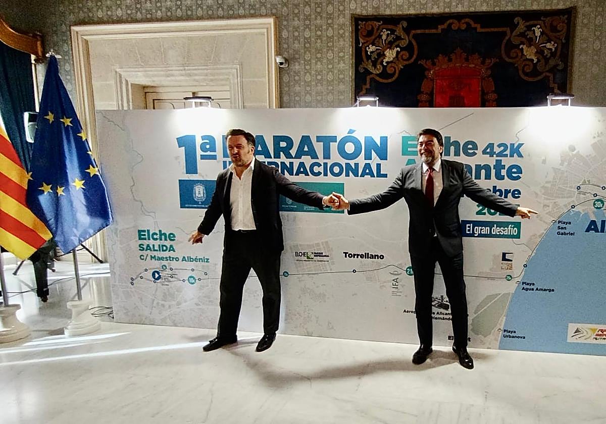 Los alcaldes de Elche y Alicante, Pablo Ruz y Luis Barcala, posan junto al cartel de la prueba.