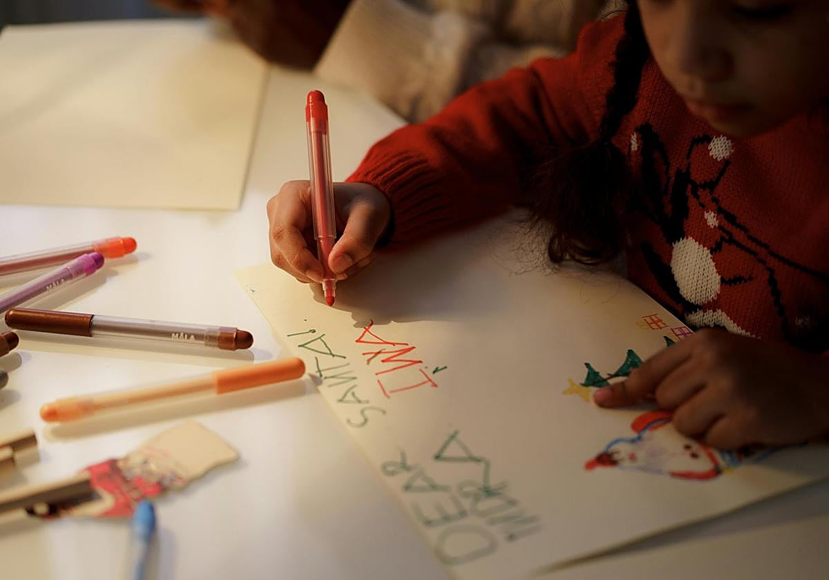 Un niño escribe una carta de Navidad.