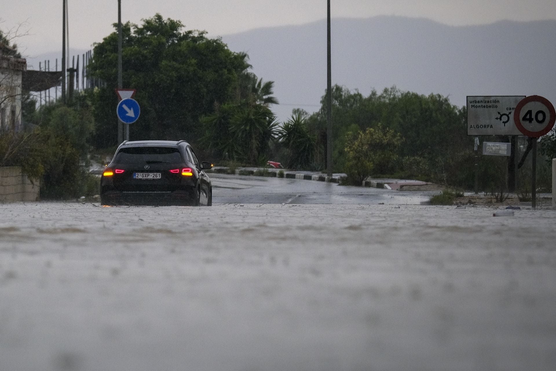 Un coche atraviesa una calle inundada.