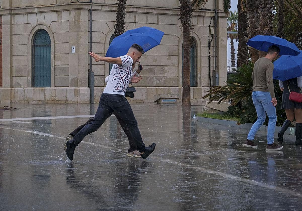 Varias personas se protegen de la lluvia en Alicante.