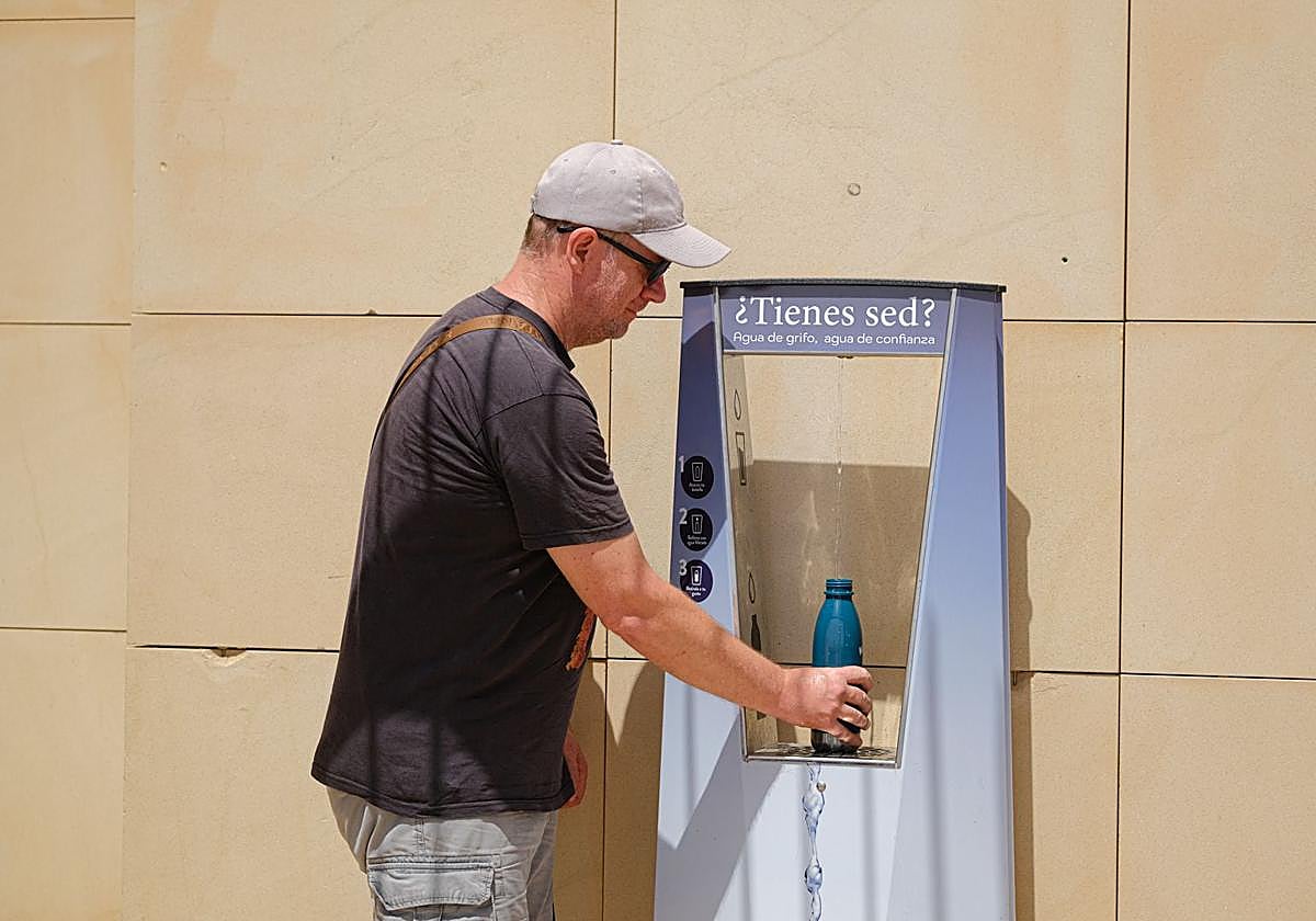 Un hombre rellena la botella en el centro de Alicante.