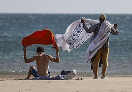 Una pareja recoge sus pertenencias de la playa por el viento.