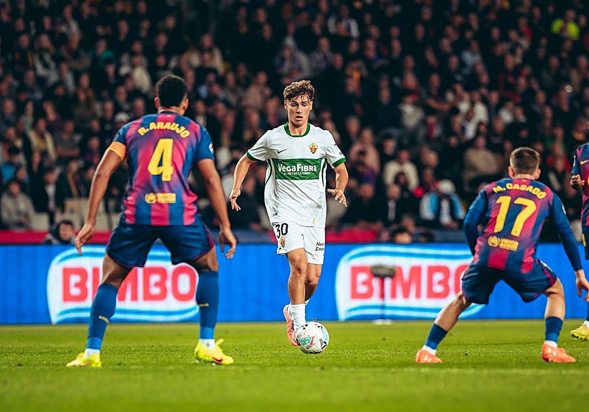 El centrocampista del Elche Rodrigo Mendoza conduce la pelota ante Araujo y Casadó.
